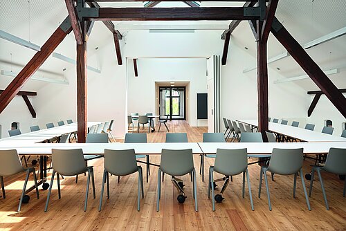 Aula chairs in bright attic meeting room with U-shaped conference tables