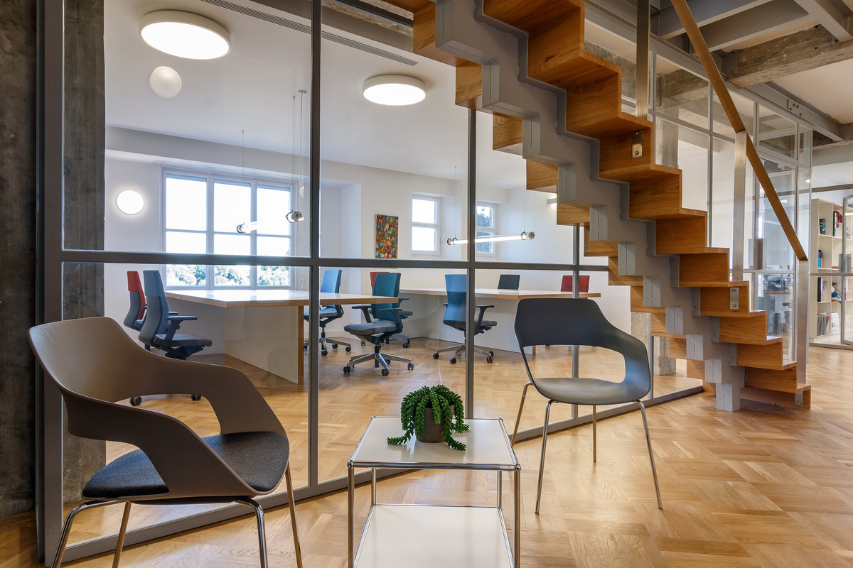 The original wooden flooring and the striking staircase were uncovered and, just like the windows, narrow strips give the glass partition walls structure. Four-leg, stackable Occo chairs (design: jehs+laub) ensure relaxed comfort.