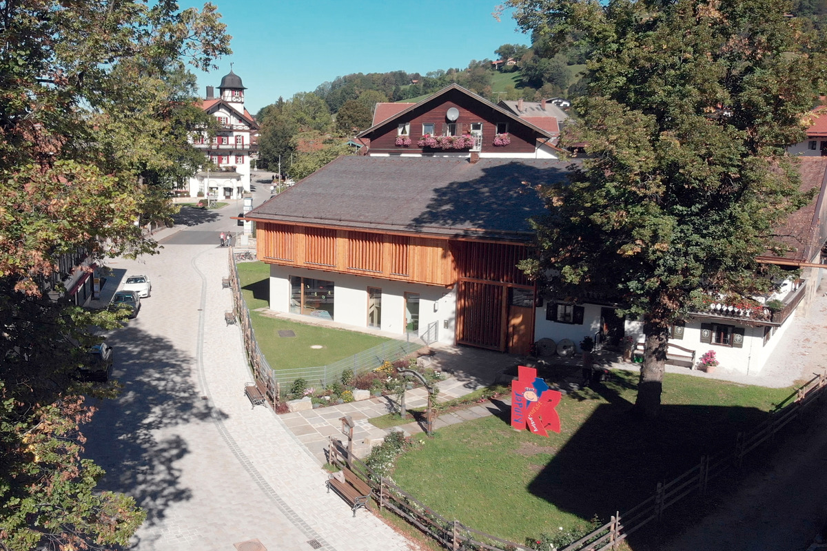 The height of the gables and eaves in the historic building is the same in the extension, but instead of a balcony, a projecting structure with vertical wooden panels and slats provides shade for the event space, which is on the top story and